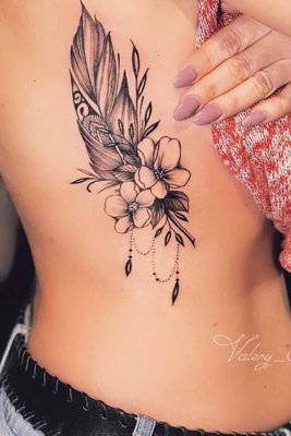 Tatouage plume avec deux fleurs sur les côtes